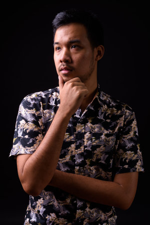 Portrait of young Asian man thinking and looking up