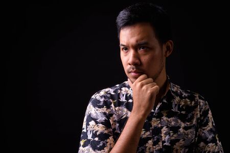 Portrait of serious young Asian man thinking and looking upの写真素材