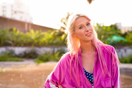 Happy young beautiful blonde woman smiling in the streets outdoors