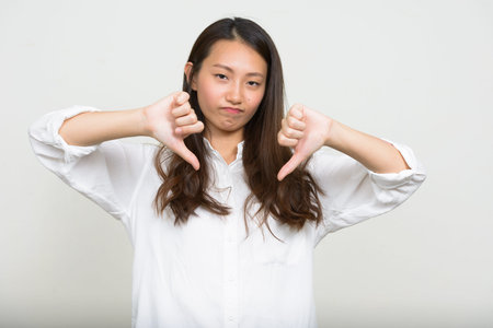 Portrait of young Asian businesswoman giving thumbs down