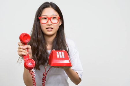 Portrait of young Asian nerd woman giving old telephoneの写真素材