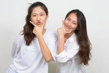 Two happy young beautiful Asian women as friends posing togetherの写真素材