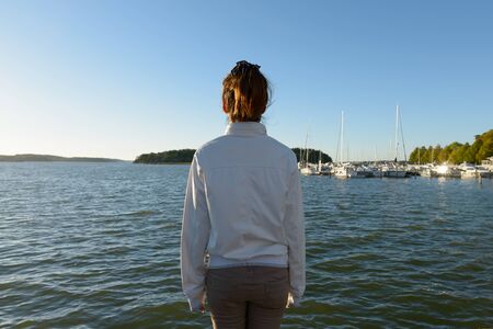 Rear view of young Asian woman looking at view of the seaの写真素材