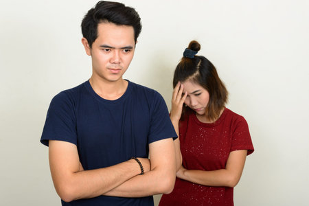 Portrait of stressed young Asian couple looking upset after fighting