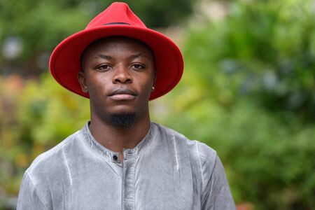 Face of young handsome African man wearing hat outdoorsの写真素材