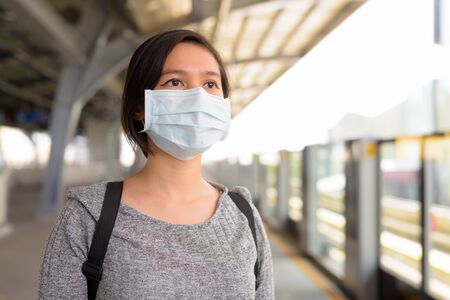 Young Asian woman with mask waiting at the sky train stationの写真素材