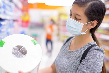 Young Asian woman with mask buying tissue paper at the supermarketの写真素材
