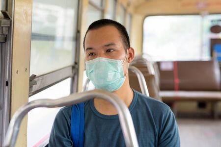 Face of young Asian man with mask riding the bus with distanceの写真素材