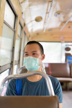Face of young Asian man with mask riding the bus with distanceの写真素材