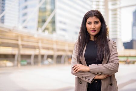 Young beautiful Indian businesswoman with arms crossed at the skywalk bridgeの写真素材