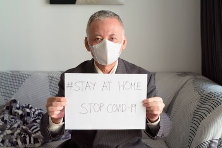 Mature Japanese businessman with mask staying at home under quarantineの写真素材
