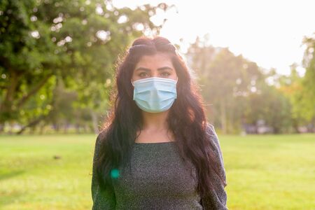 Young Indian woman with mask for protection from corona virus outbreak at the parkの写真素材