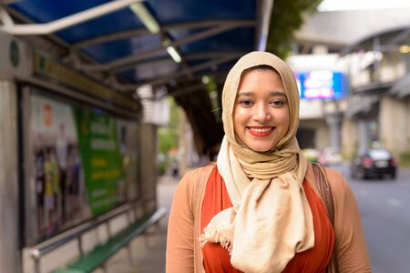 Happy young beautiful Indian Muslim woman smiling at the bus stopの写真素材