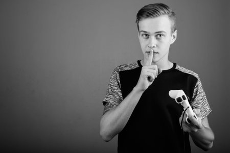 Young handsome man with blond hair against gray background