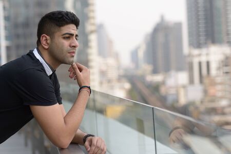Portrait of young handsome Indian man thinking in the cityの写真素材