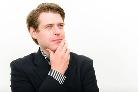 Portrait of young handsome businessman thinking and looking up
