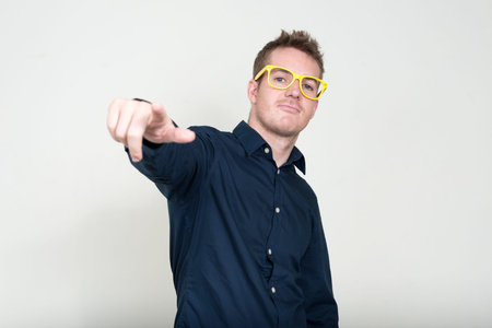Portrait of handsome businessman with eyeglasses pointing at camera