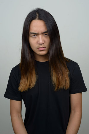 Stressed young Asian man with long hairの写真素材