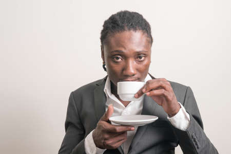 Young handsome African businessman with dreadlocks drinking coffeeの写真素材