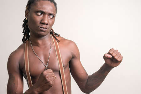 Stressed young muscular African man with dreadlocks ready to fight shirtlessの写真素材