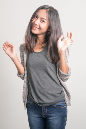Happy young beautiful Asian teenage girl waving hand