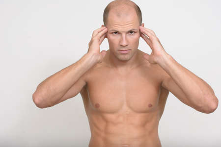 Stressed young muscular bald man having headache shirtlessの写真素材