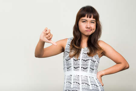 Portrait of stressed young Asian woman giving thumbs downの写真素材