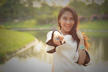 Happy Asian businesswoman pointing at camera at the parkの写真素材