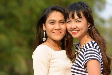 Portrait of two happy young Asian women together at the park
