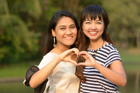 Portrait of two happy young Asian women together at the park