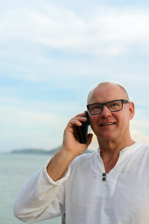 Mature handsome tourist man against view of the beach outdoors