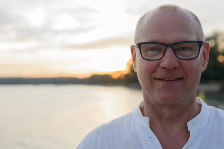 Mature handsome tourist man against view of the beach outdoorsの写真素材