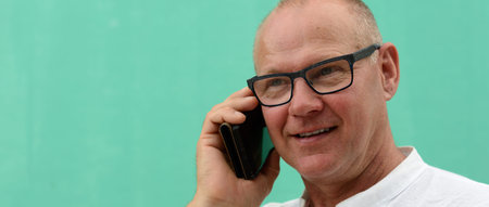 Mature handsome tourist man against green wall outdoors