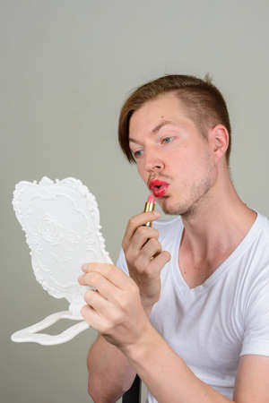 Portrait of young man with beard stubble wearing makeupの写真素材