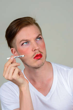 Portrait of young man with beard stubble wearing makeupの写真素材