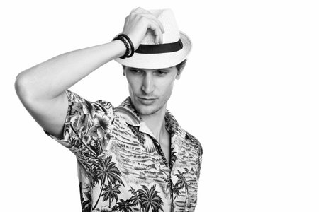 Studio shot of young handsome man posing while holding hat