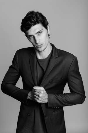 Studio shot of young handsome businessman holding jacket against gray backgroundの写真素材