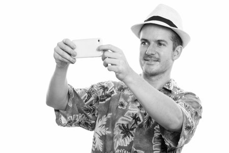 Studio shot of happy man smiling while taking picture with mobile phone