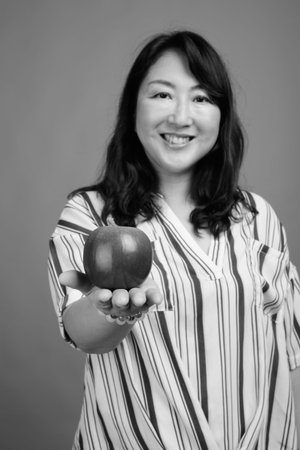 Portrait of mature beautiful Asian businesswoman with apple