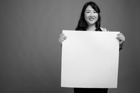 Portrait of mature beautiful Asian businesswoman with white board