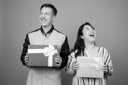 Portrait of young handsome businessman and mature Asian businesswoman together with gift box