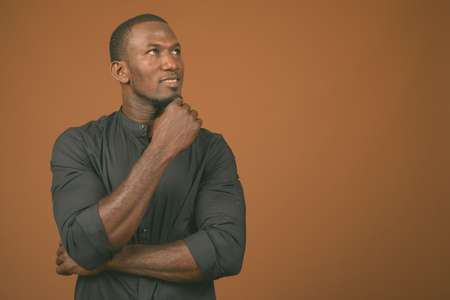 Portrait of handsome African businessman against brown backgroundの写真素材
