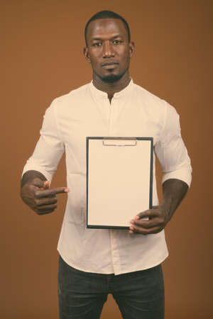 Portrait of handsome African businessman against brown backgroundの写真素材