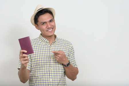 Portrait of happy handsome Asian tourist man showing passportの写真素材