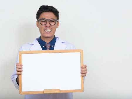 Portrait of happy handsome Asian man doctor smiling