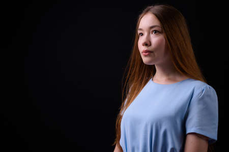 Young beautiful woman with long brown hair against black backgroundの写真素材
