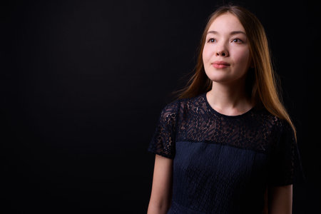 Young beautiful woman with long brown hair against black background