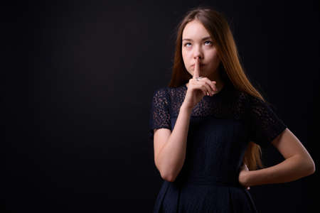 Young beautiful woman with long brown hair against black backgroundの写真素材
