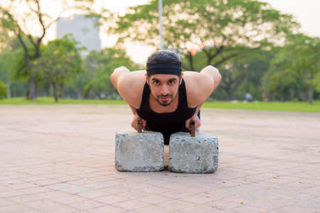 Young handsome bearded Indian man exercising at the parkの写真素材