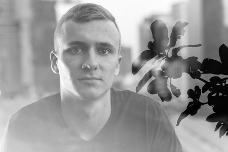 Portrait of young blond man against view of the city in multiple exposure
